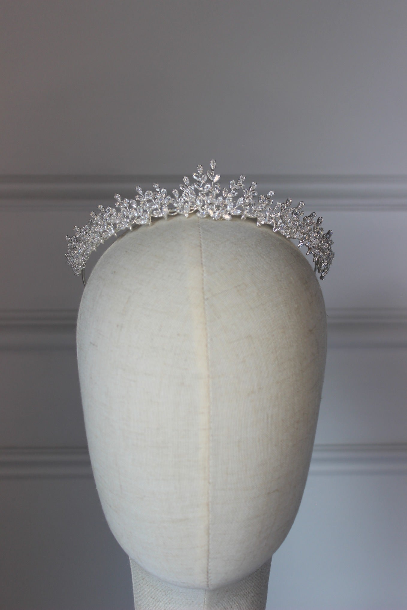 Silver tiara on a mannequin head against a plain background