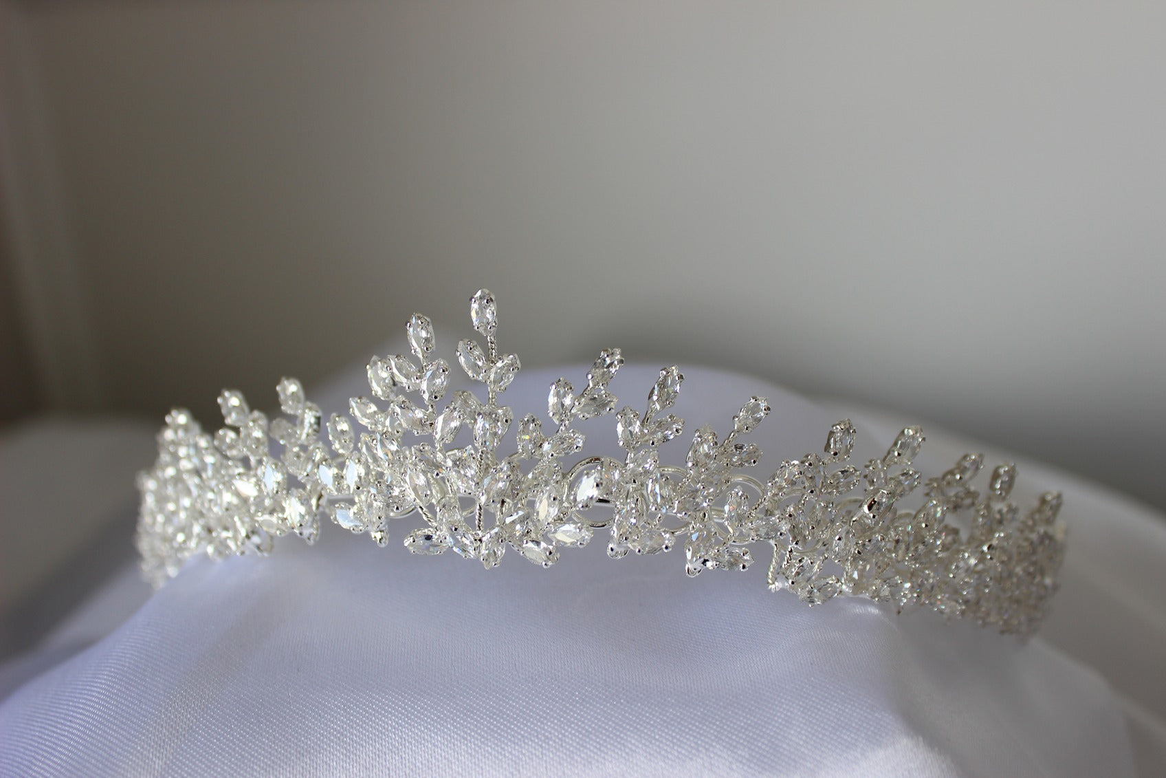 Silver tiara on a white fabric background