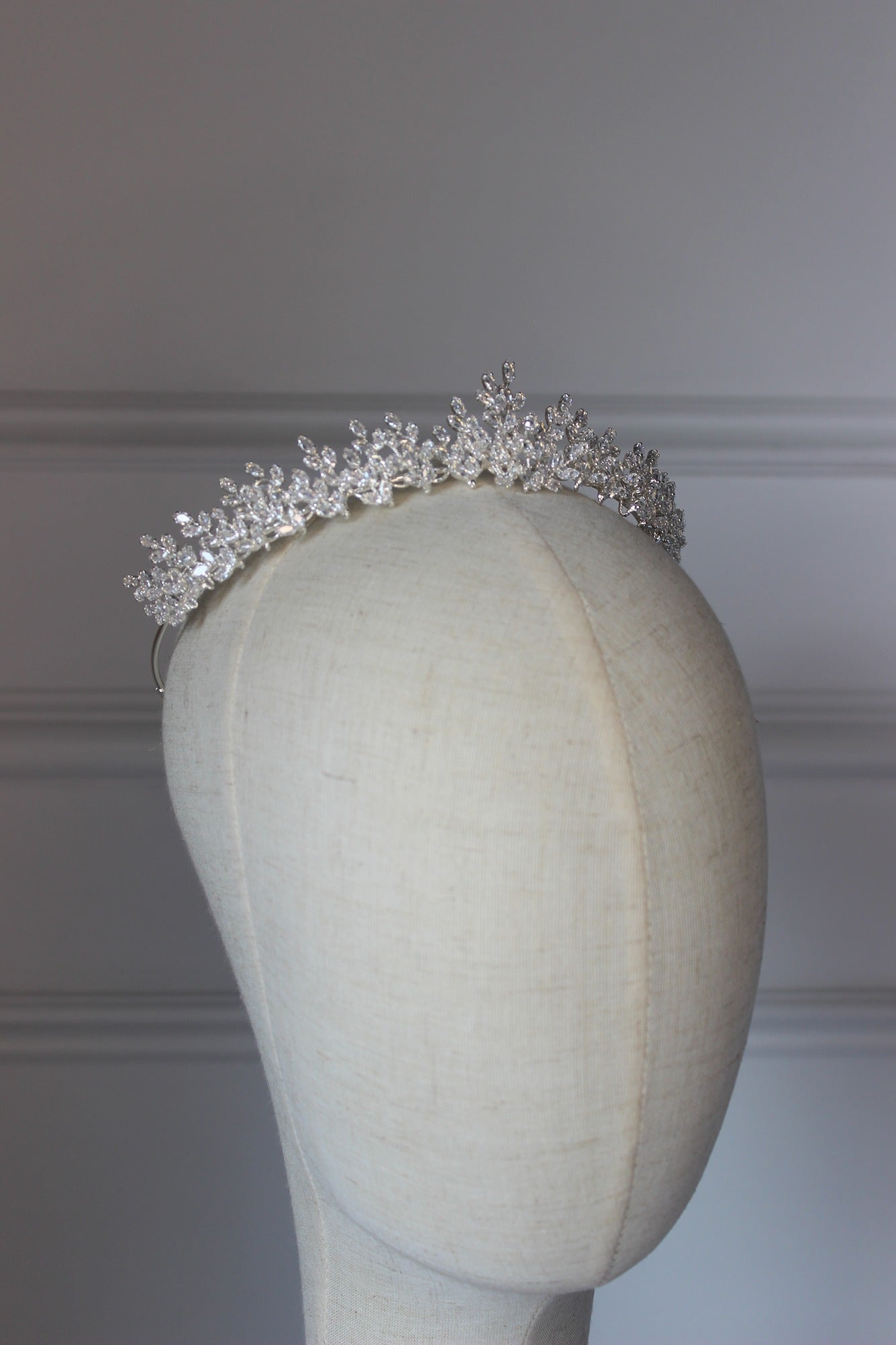 Silver tiara on a mannequin head against a plain background
